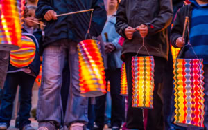 Lampions allumés multicolores tenus par des enfants participant à un défilé de fête à Sainte-Sévère-sur-Indre.