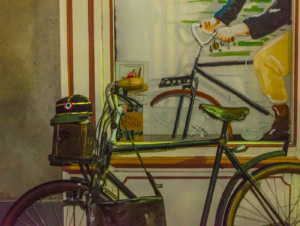 Réplique du vélo du facteur de Jour de fête adossée à une vitrine peinte, avec képi et sacoche, de nuit à Sainte-Sévère-sur-Indre.
